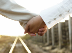 Couple Holding Hands on a Railroad Track